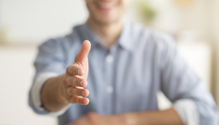 Happy person extending their hand out for a welcoming handshake.